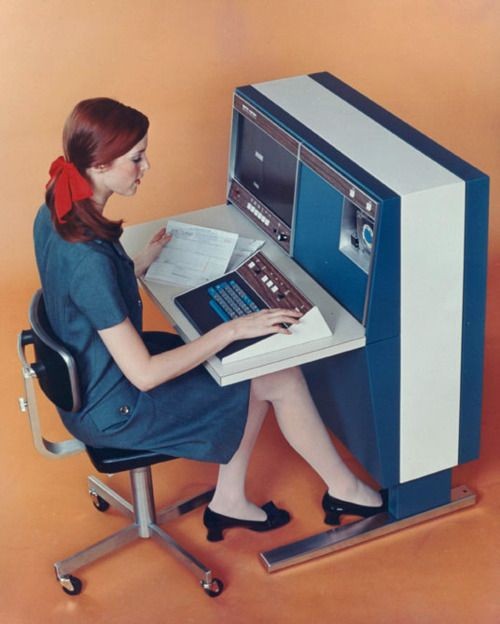 Woman working at an orange desk with a vintage computer